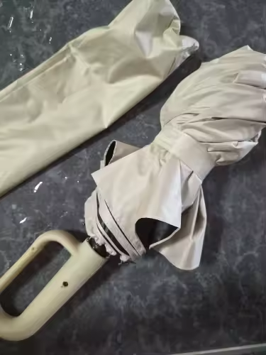 Beige umbrella next to its sleeve, photographed as delivered