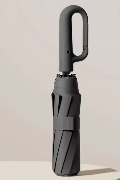 Folded black umbrella standing on a pale podium, loop handle on top